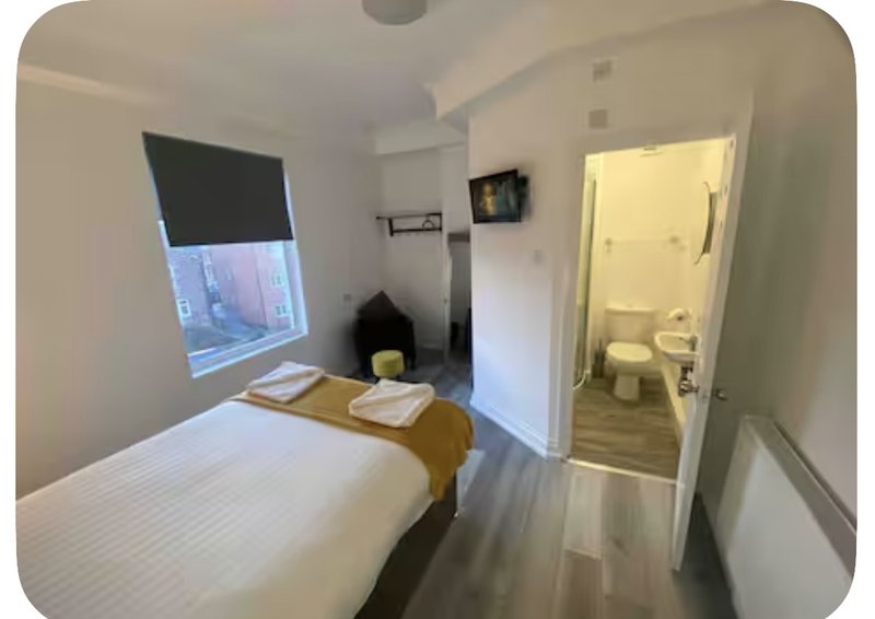 Small bedroom with single bed, window, desk area, and en-suite bathroom door