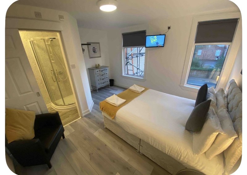 Bright modern bedroom with double bed, en-suite bathroom, wall-mounted TV and windows