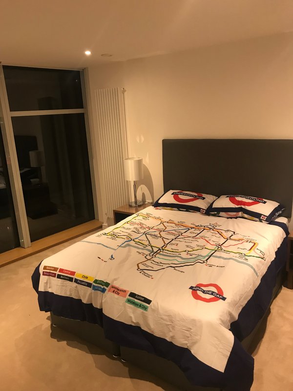Bedroom with double bed, black headboard, London Underground map bedding, wardrobe and radiator