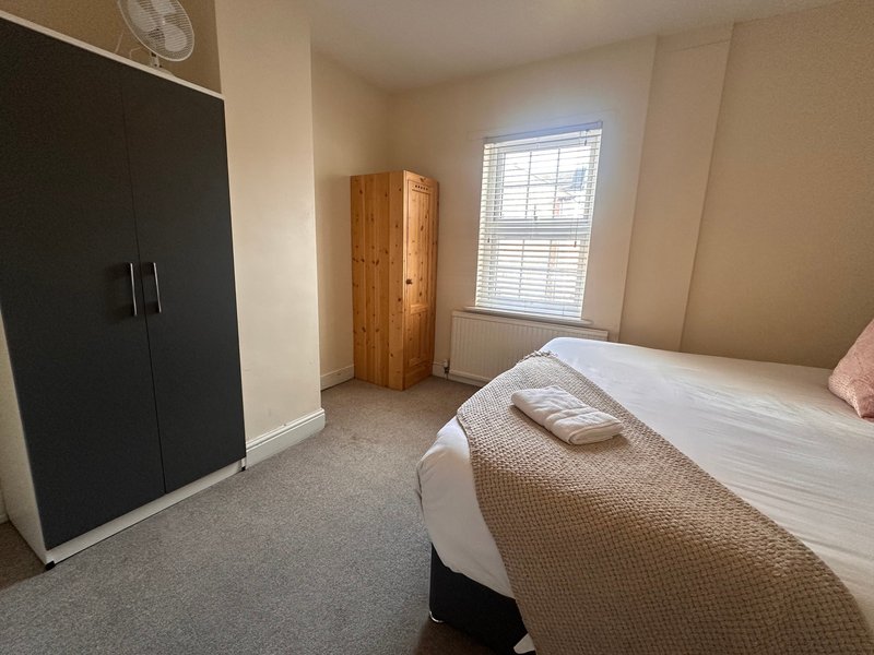 Bedroom with double bed, wooden wardrobe, black fitted wardrobes and window with shutters