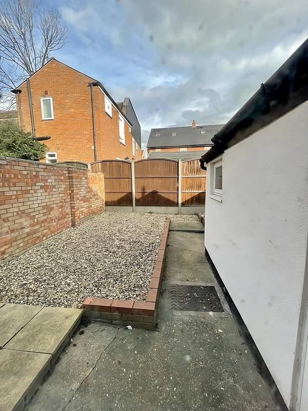 Brick property exterior with wooden gate, gravel courtyard and paved pathway