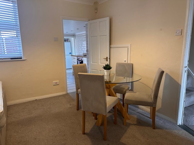 Dining room with round glass table, four upholstered chairs, and cream walls