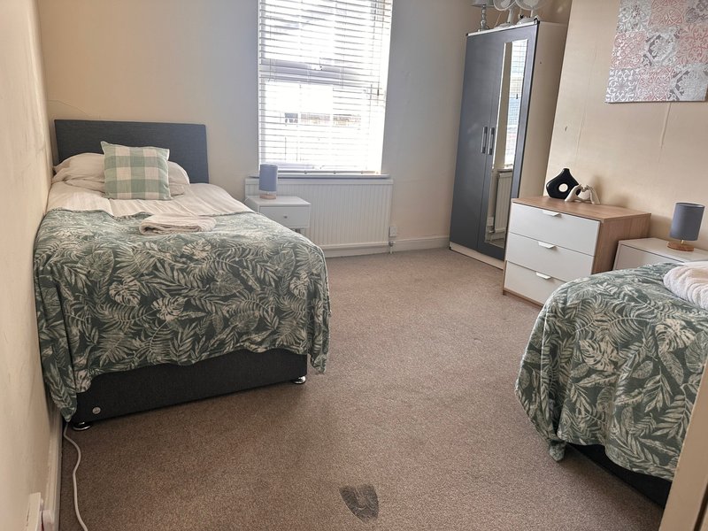 Bedroom with two single beds, patterned bedding, wardrobe and chest of drawers