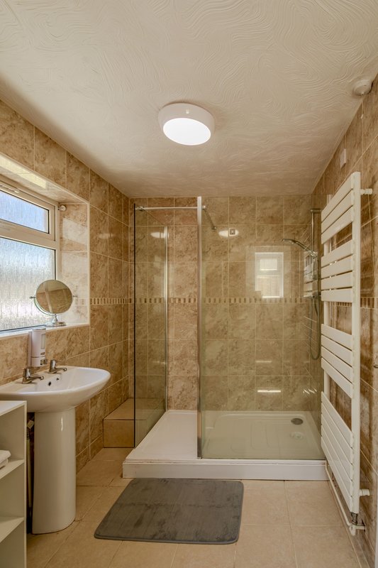 Modern bathroom with walk-in shower, pedestal sink, heated towel rail and skylight