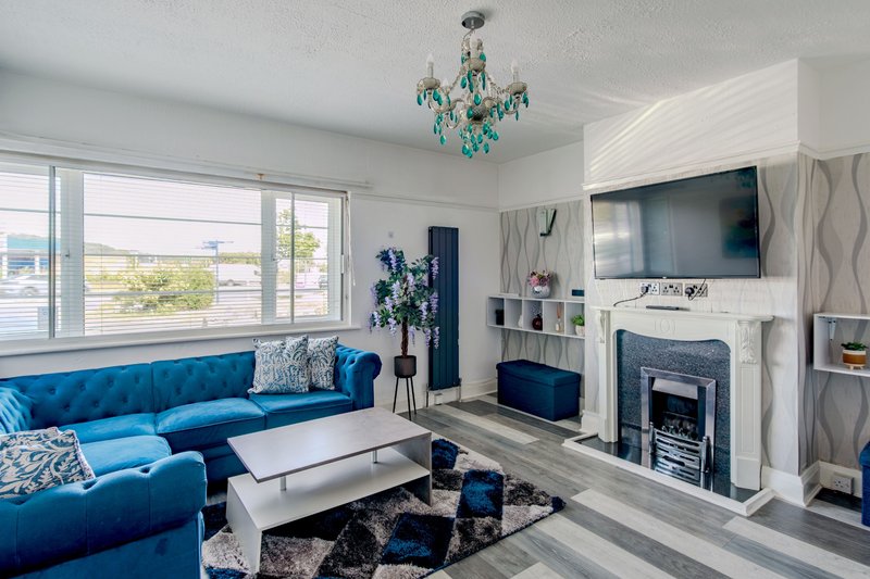 Modern living room with blue sectional sofa, fireplace, TV, and large windows