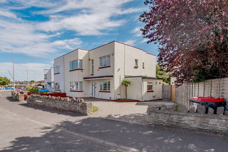 Modern two-story white building with driveway, garden landscaping and street frontage