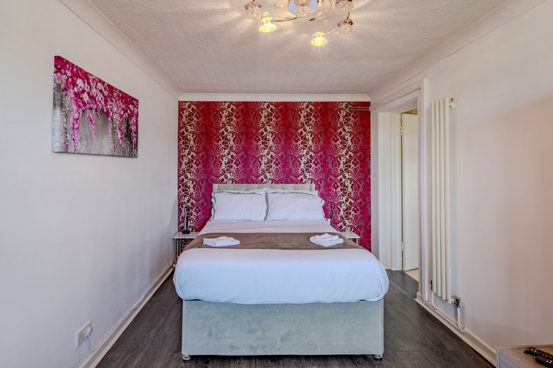 Modern bedroom with double bed, red patterned headboard, white bedding, and ceiling lights