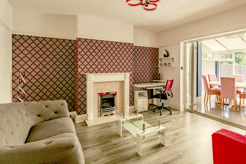 Spacious living room with patterned wallpaper, fireplace, sofa, glass table and open-plan dining area
