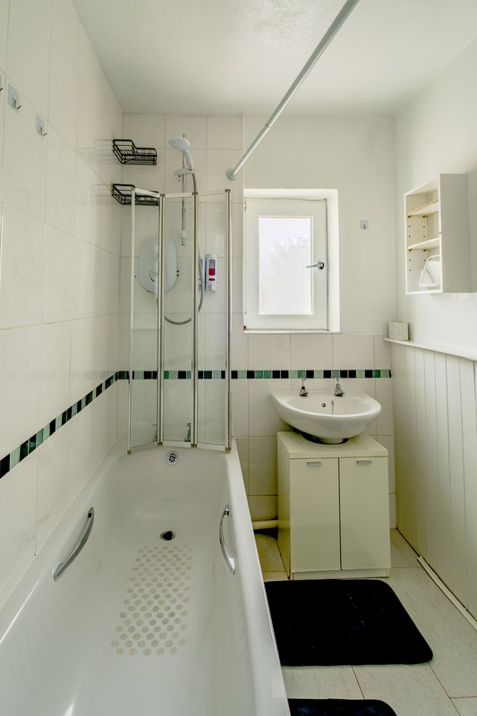 Clean white bathroom with bathtub, shower enclosure, sink vanity and window