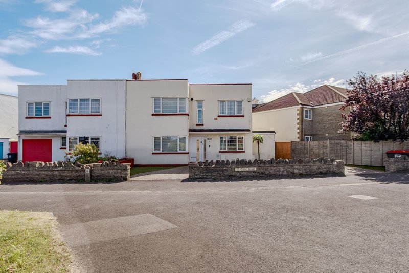 Modern white two-storey house with driveway, red garage door, and front garden
