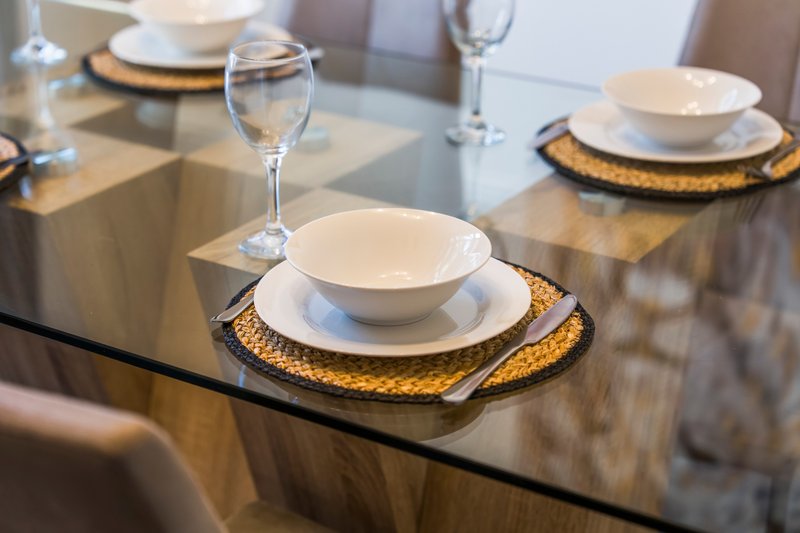 Formal dining table set with white bowls, gold placemats, and wine glasses
