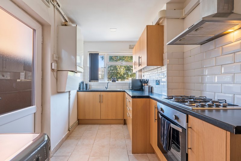 Modern kitchen with wooden cabinets, black countertops, gas range and white subway tile backsplash