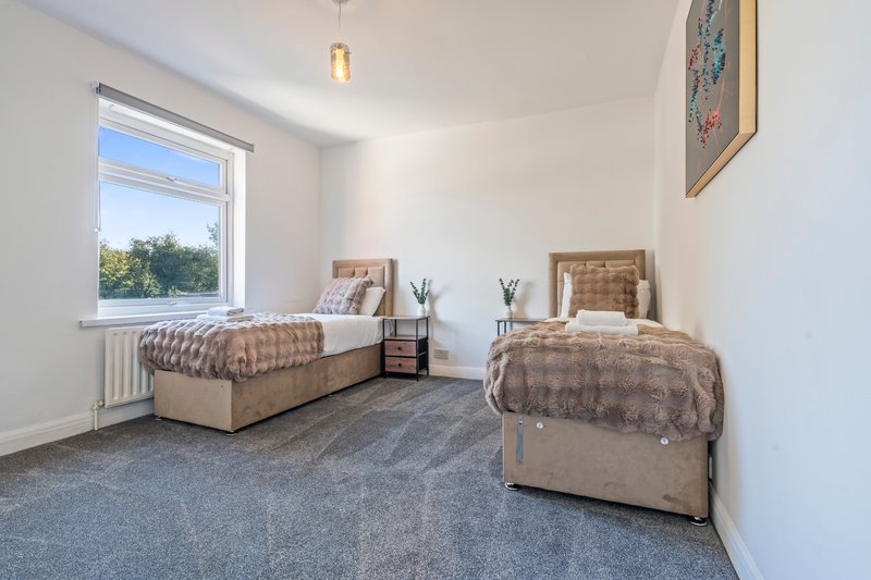 Bedroom with two single beds, window with garden view, and neutral décor