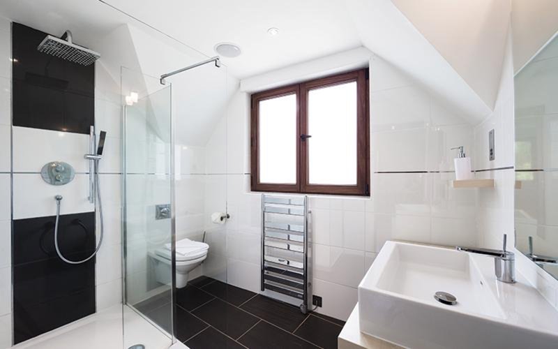Modern bathroom with walk-in shower, white sink, toilet, and heated towel rack