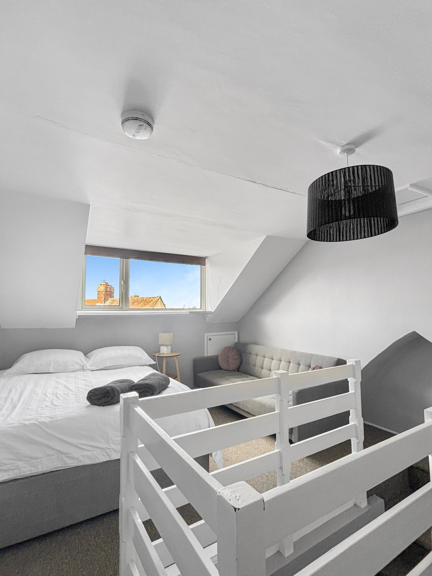 Modern attic bedroom with double bed, bunk bed, window and pendant lighting