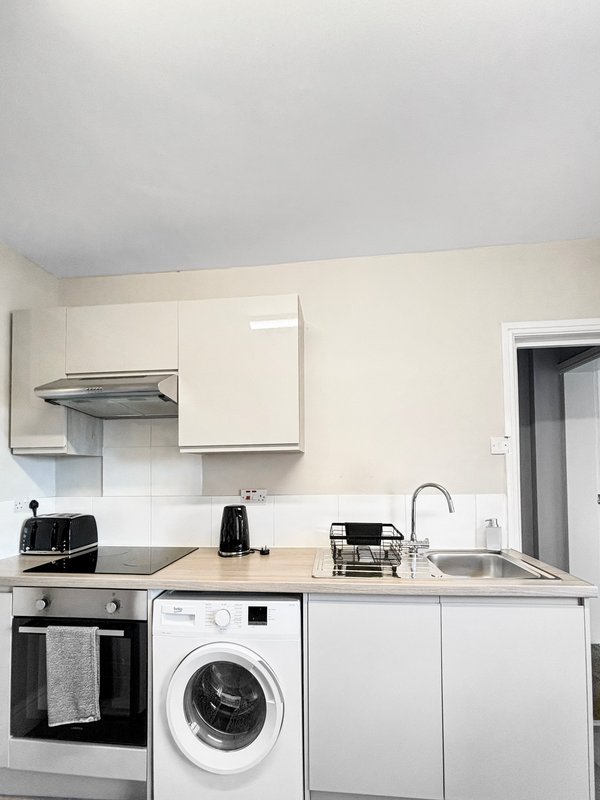 Modern kitchen with white cabinets, integrated appliances, and stainless steel sink