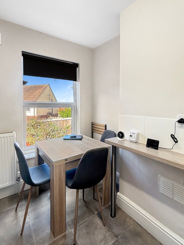 Home office with wooden desk, two black chairs, window overlooking garden