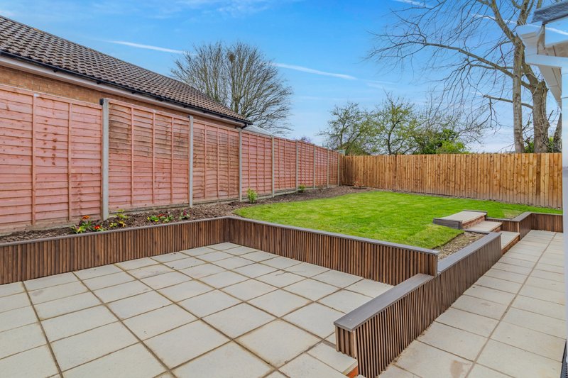 Garden with paved patio, raised planter beds, wooden fence and lawn area
