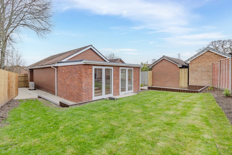 Modern brick bungalow with garden, patio doors and manicured lawn