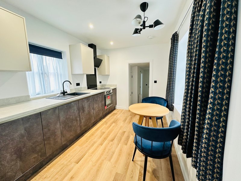 Modern kitchen with dark cabinetry, white countertop, dining table and blue chair