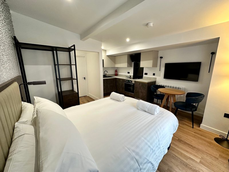 Modern studio bedroom with double bed, kitchenette, bathroom and wall-mounted TV