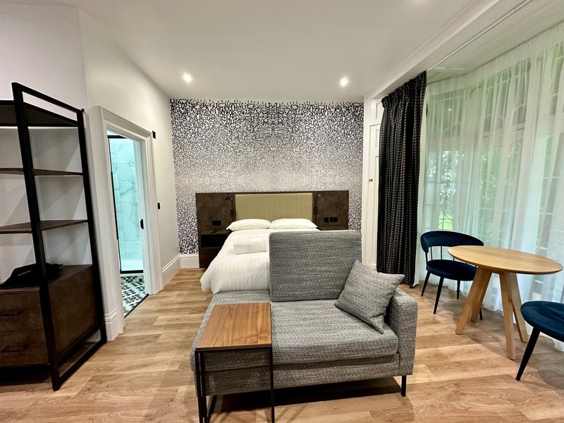Modern bedroom with double bed, grey sofa, wooden floor, and contemporary furnishings