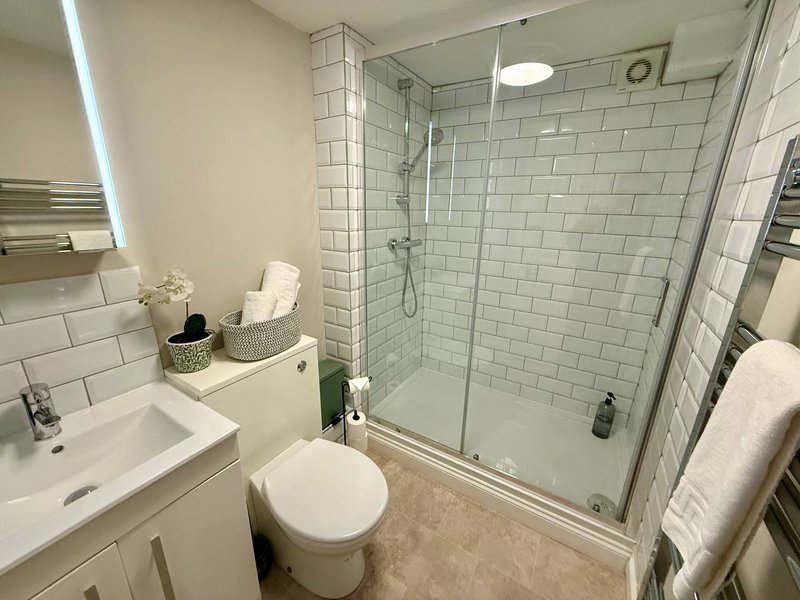 Modern bathroom with white subway tile shower, toilet, sink and towel rack