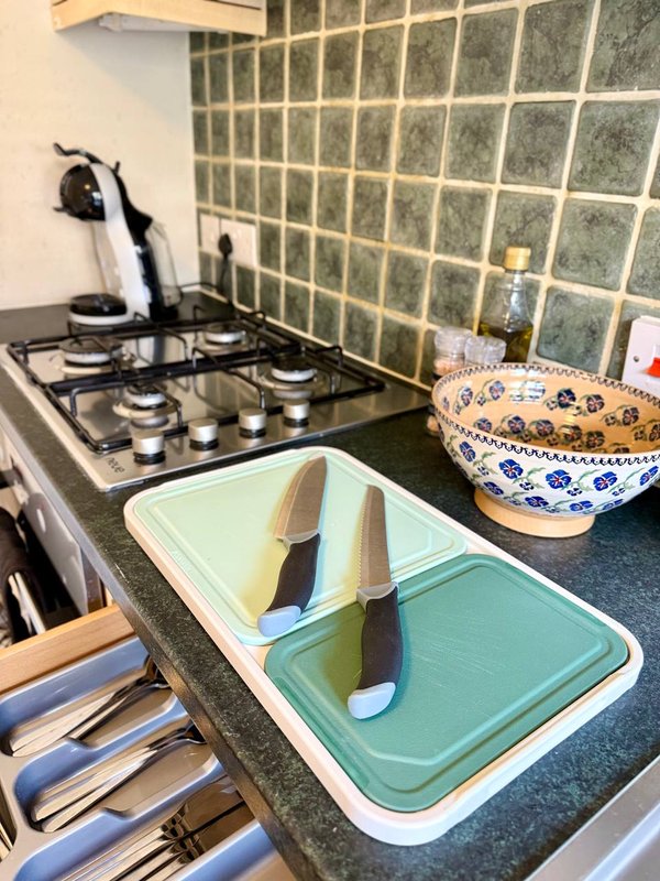 Kitchen countertop with gas hob, cutting boards, knives, and decorative bowl