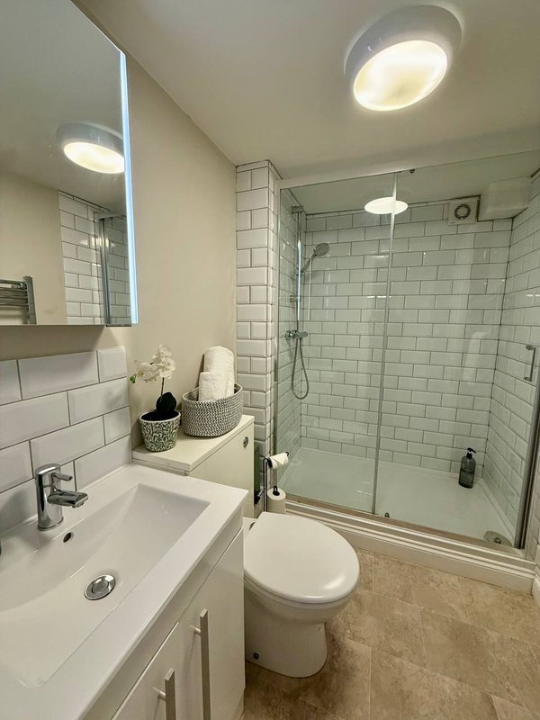 Modern bathroom with white subway tile, double sink vanity, toilet, and glass-enclosed shower