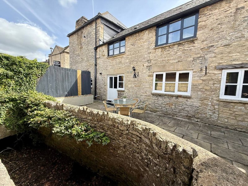 Stone cottage exterior with patio area, garden hedge, and ivy-covered wall