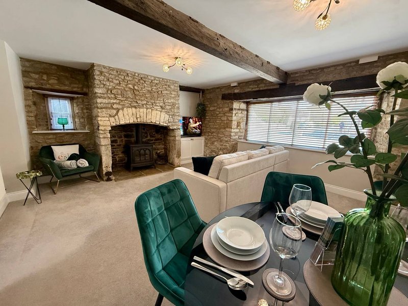 Open-plan living room with fireplace, dining table, cream sofa and green armchairs