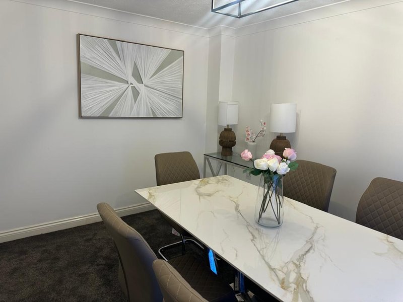 Modern dining room with marble table, upholstered chairs, abstract wall art and fresh flowers