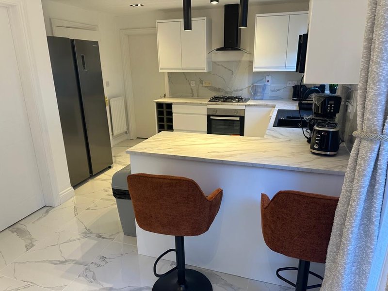 Modern kitchen with white cabinetry, island seating, and stainless steel appliances