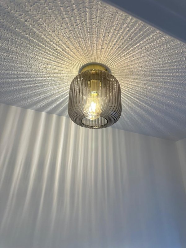 Ceiling-mounted pendant light with decorative metallic shade casting geometric pattern