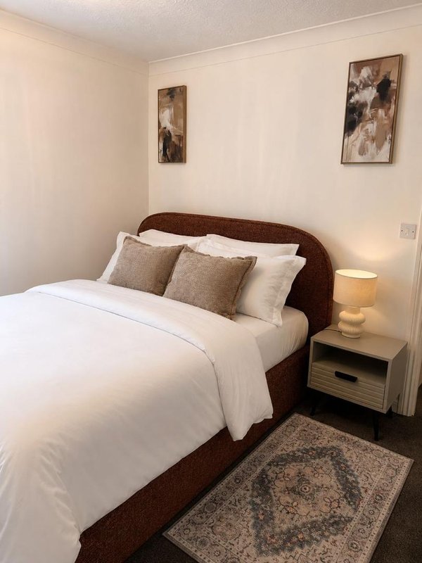 Bedroom with double bed, brown headboard, white bedding, and framed wall art