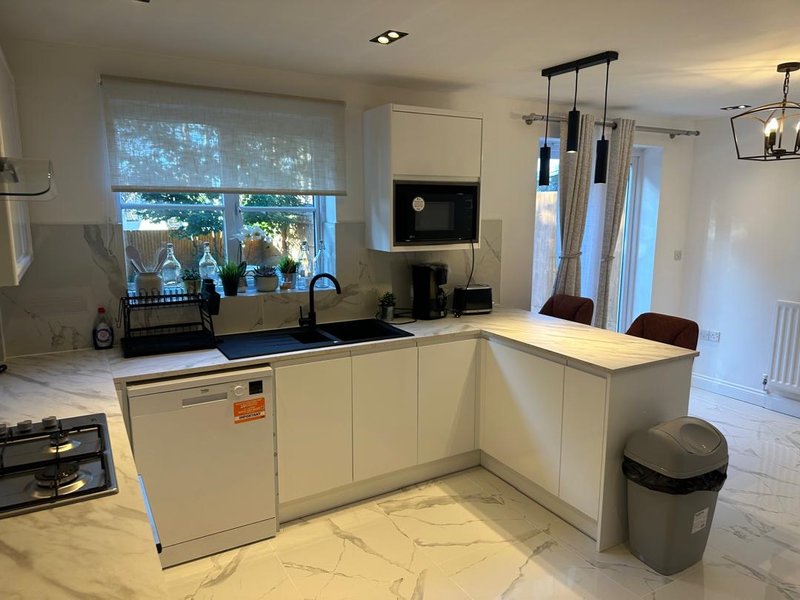 Modern kitchen with white cabinetry, black countertop, island seating, and garden view