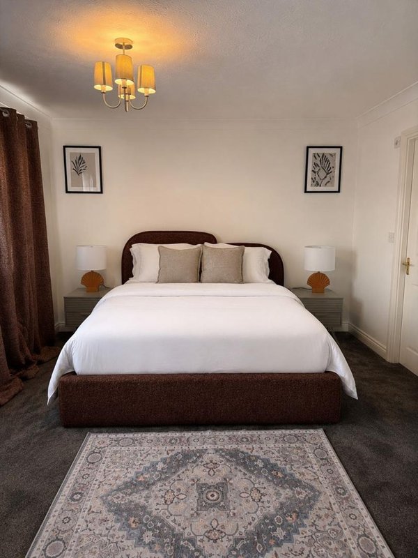 Modern bedroom with double bed, bedside lamps, framed wall art, and ceiling light fixture
