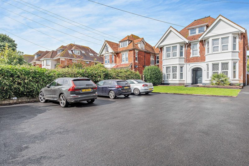 Brick detached house with driveway, parked cars, and neighbouring properties visible