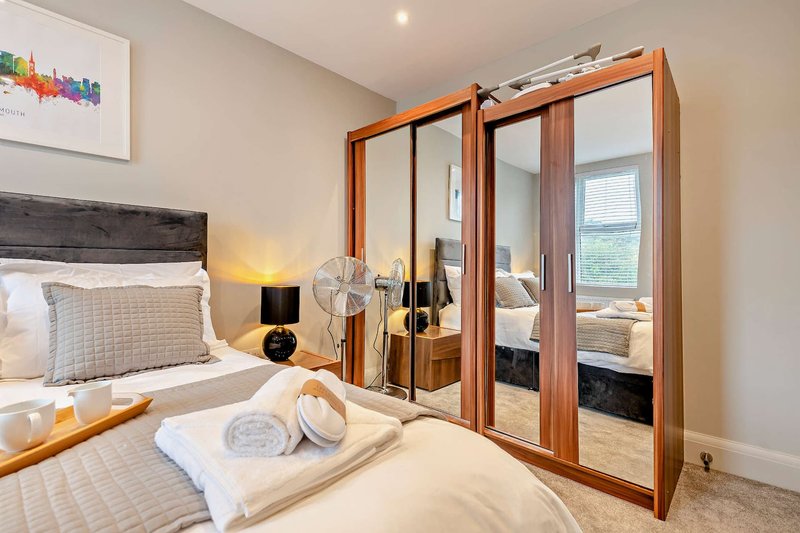 Modern bedroom with double bed, wooden wardrobe, bedside lamp and framed artwork