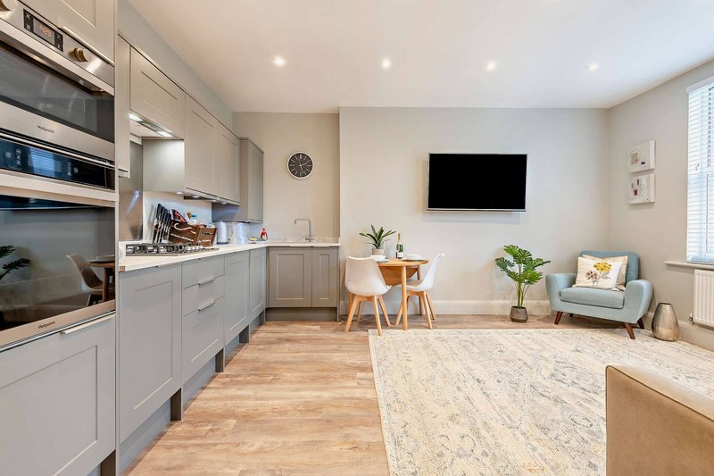 Open-plan kitchen and living area with white cabinetry, wooden flooring, and modern furnishings