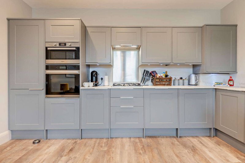Modern kitchen with grey cabinetry, built-in oven, gas hob, stainless steel fridge and wooden flooring
