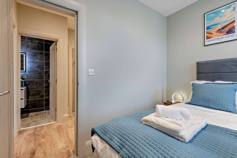 Bright bedroom with double bed, blue bedding, white towels, and ensuite bathroom visible