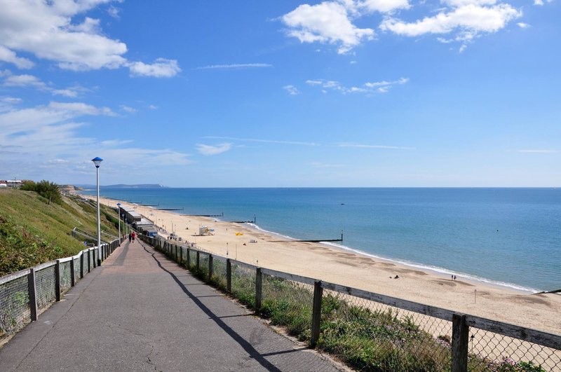 Coastal pathway with railings overlooking sandy beach and blue sea