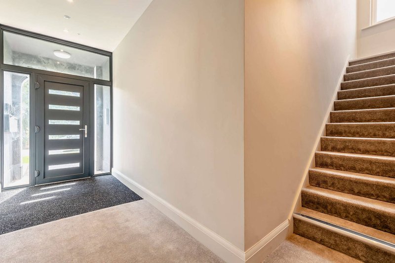 Bright hallway with modern front door, stairs and neutral decor
