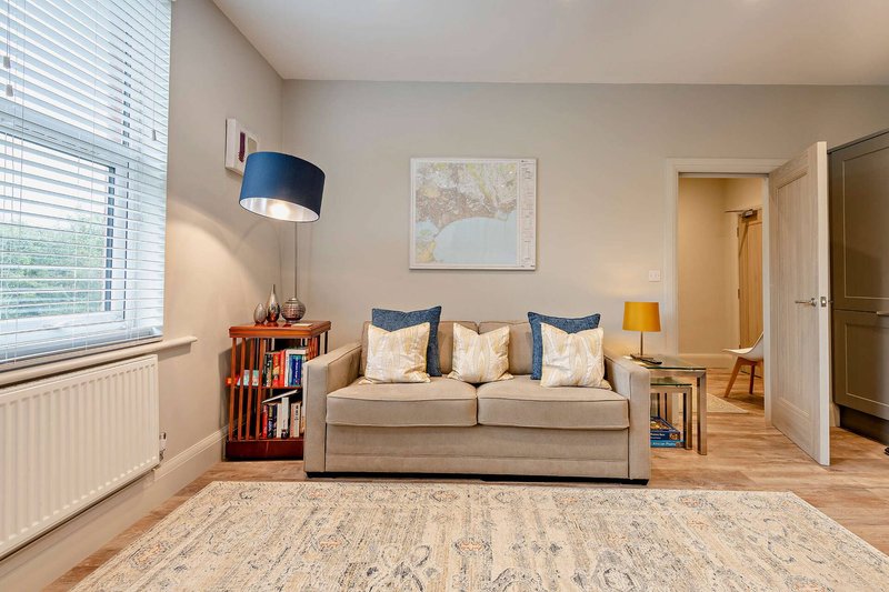 Bright living room with beige sofa, blue pendant lamp, wooden bookshelf and map artwork