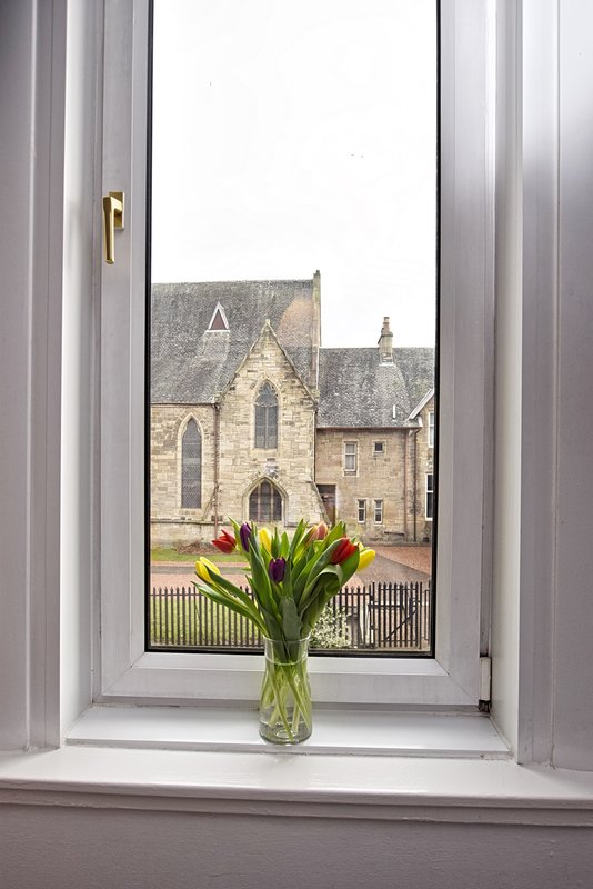 Window view of stone church with flowers in vase on sill