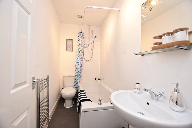 Modern bathroom with white sink, toilet, shower cubicle and heated towel rail