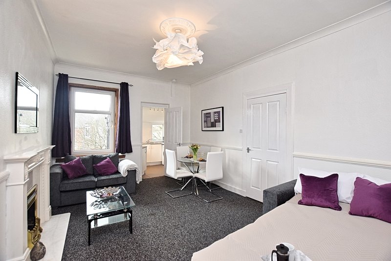 Spacious bedroom with bed, sofa seating area, dark carpet and modern ceiling light