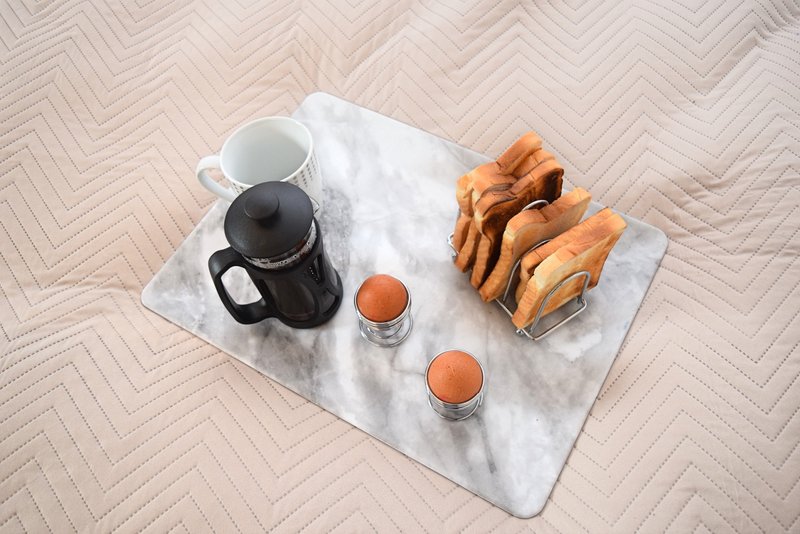Marble tray with coffee pot, cups, pastries and beverages on herringbone floor