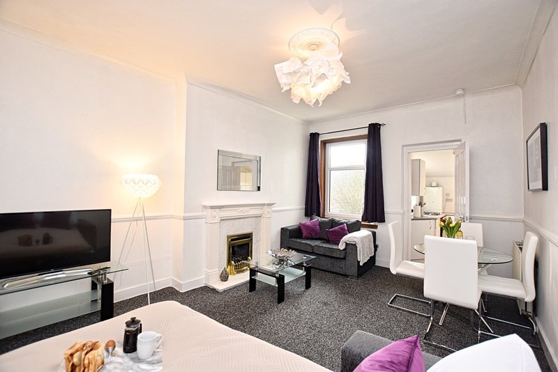 Modern living room with fireplace, TV, bed, armchair and purple accents